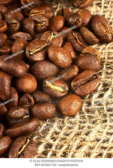 Roasted coffee beans on burlap background. Macro shot with tilt effect