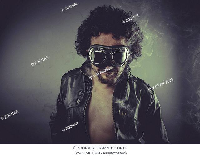 Biker speed, man with googles and black coat, smoke and dark background