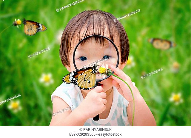 little asian girl with magnifying glass outdoors in the day time