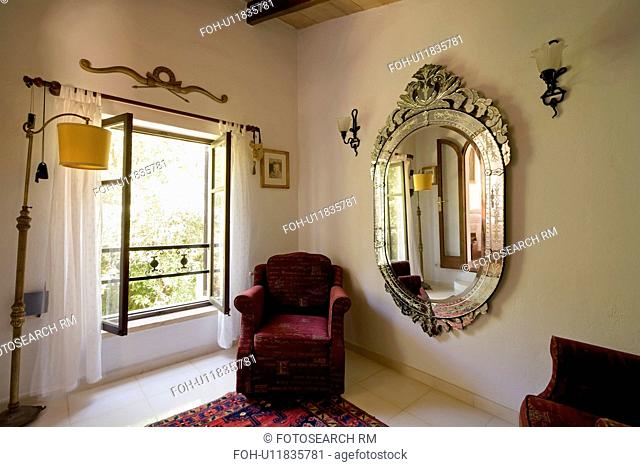 Maroon armchair and large Venetian mirror in dressingroom with white curtains