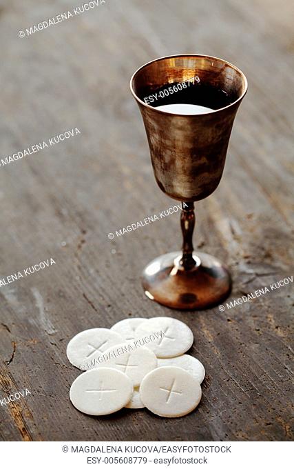 Chalice with wine and communion wafers on wooden background