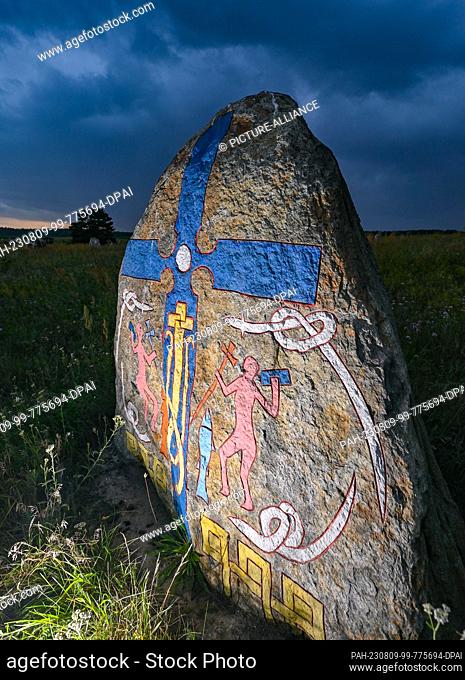 08 August 2023, Brandenburg, Henzendorf: Figures carved and painted in stone can be seen on an erratic boulder in the grounds of the Henzendorf erratic boulder...