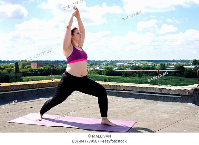 Young woman doing yoga on the roof of a building