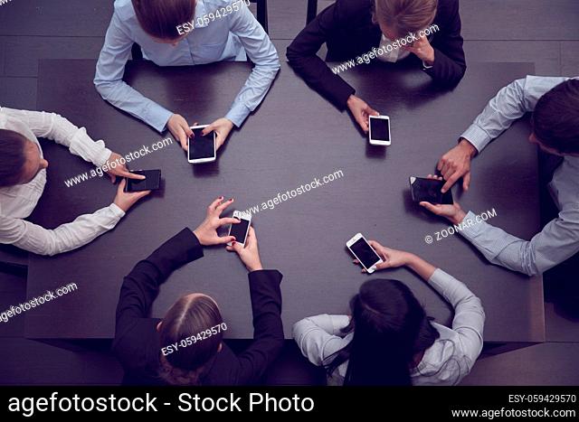 Business people with blank phones sitting around the table using app, top view