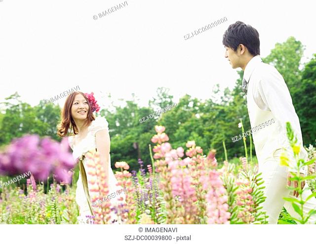 Bridal couple walking through a field of flowers
