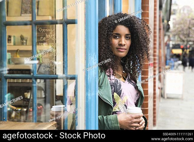 Woman walking out of cafe with coffee in hand