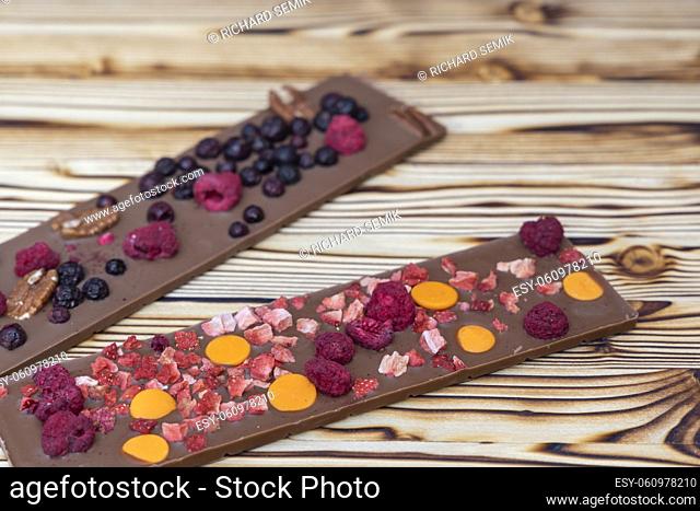 different kinds of chocolate with dried fruits on a wooden board