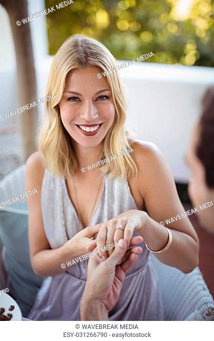 Man putting engagement ring on womans hand
