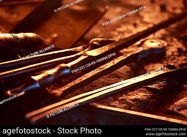 28 November 2023, Saxony-Anhalt, Wernigerode: Forging tools for the production of a Celtic sword lie in the light of the flames at the forge fire in the Harz...