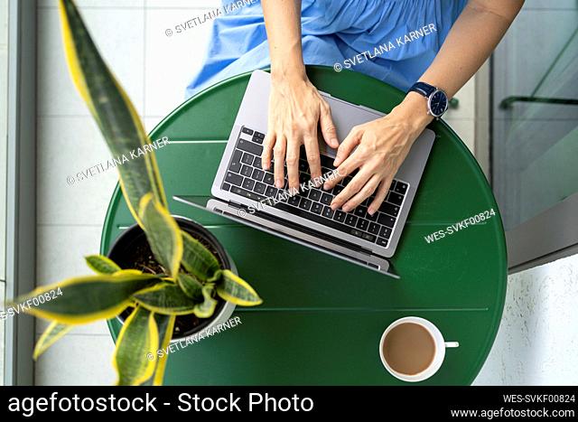 Hands of businesswoman using laptop at table
