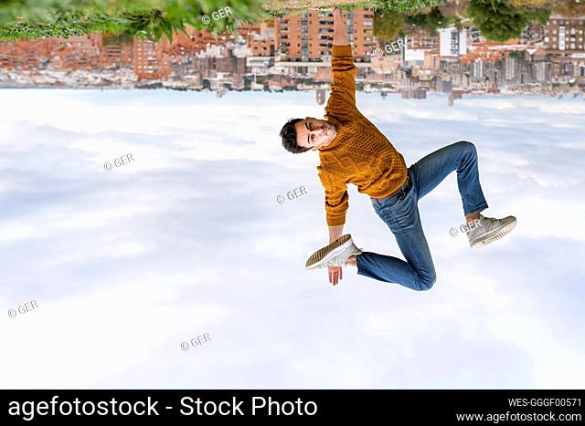 Upside down image of young man doing handstand against city