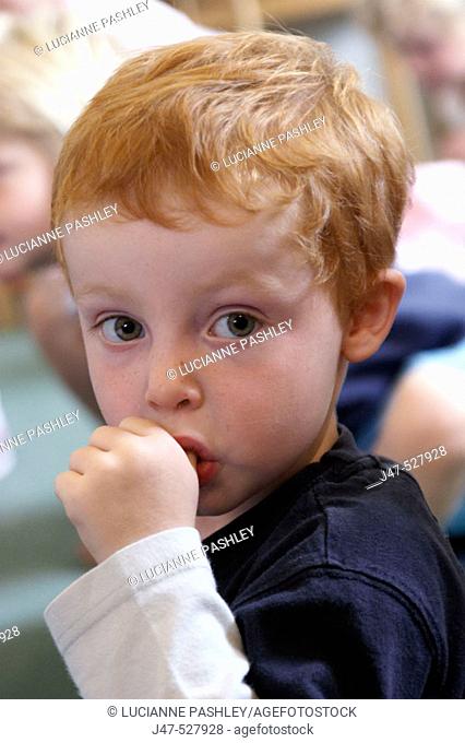 3 year old boy, looking into camera, sucking his thumb