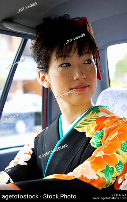 Beautiful Japanese woman in kimono in back seat of taxi
