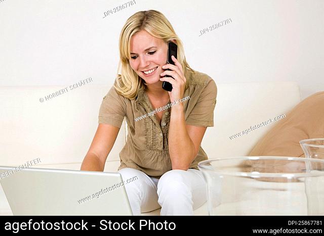 Woman Using Laptop Computer and Talking on Cellular Phone