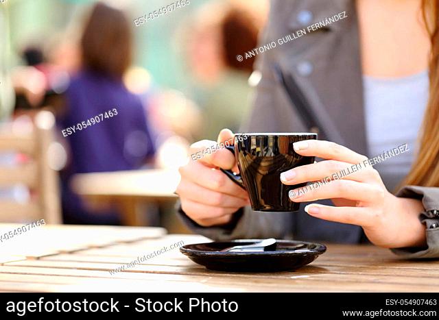 Close up of a woman hands holding a coffee cup on a cafe terrace