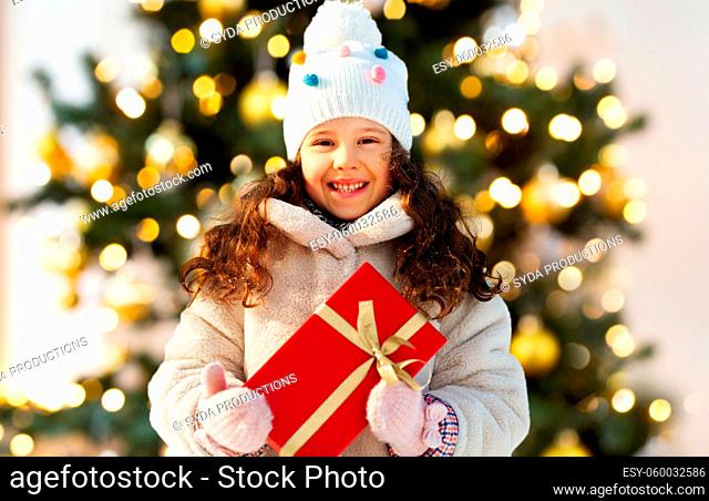 happy little girl with gift over christmas tree
