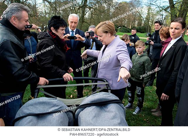 German Chancellor Angela Merkel (CDU) looks at the twins of Saxony's Prime MInister Stanislaw Tillich (CDU, back) at the Fuerst Pueckler park during the closure...