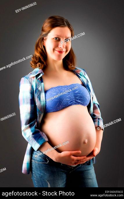 Happy young pregnant woman on gray background