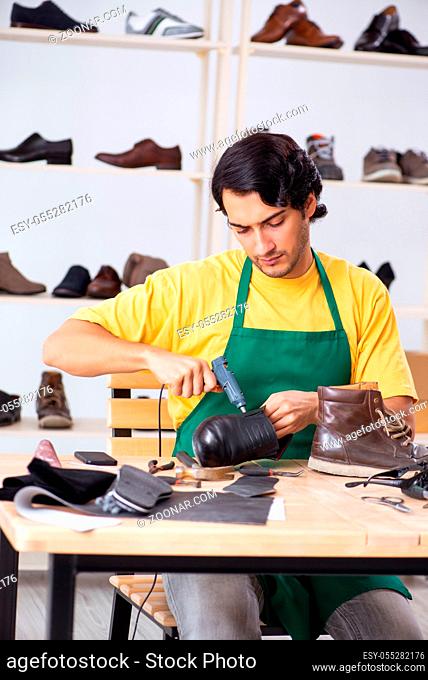 Young man repairing shoes in workshop