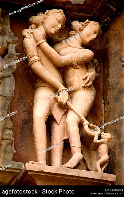 Stone wall panel of amused couple playfully engaged with a monkey at Lakshman Temple in Khajuraho, Madhya Pradesh, India, Asia