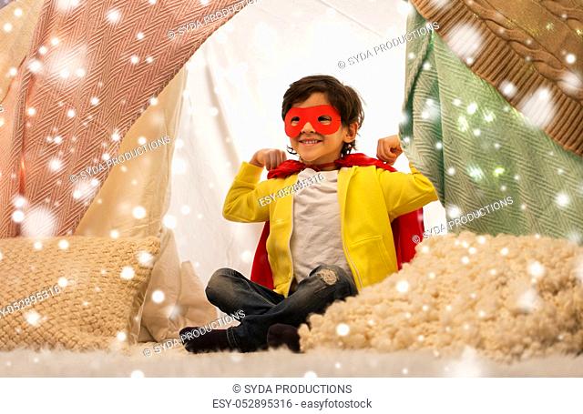 happy boy in super hero cape in kids tent at home