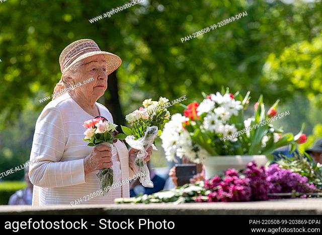 08 May 2022, Saxony, Dresden: A woman has two bouquets of flowers in her hand, which she wants to lay on the monument. About 150 people came to Dresden's...