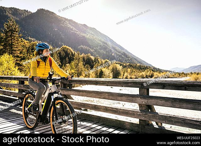 Woman with crash helmet cycling on bridge