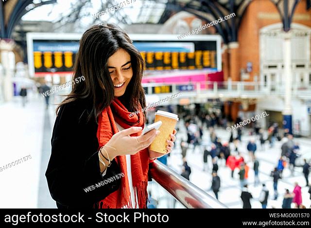 UK, London, Young woman using mobile phone at train station