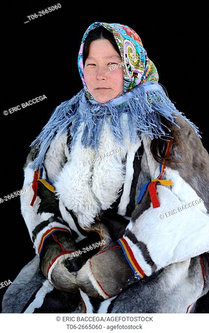 Ekaterina Yaptik, portrait of Nenets herder woman dressed in her winter coat made with reindeer fur / skin. The collar is made with arctic fox fur and black...