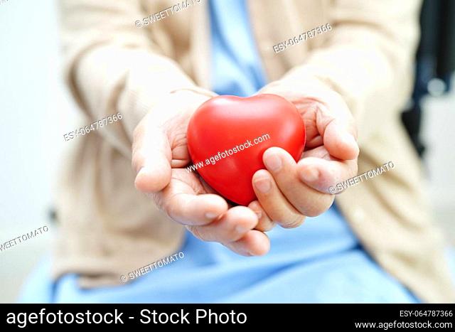 Asian elder senior woman patient holding red heart in hospital