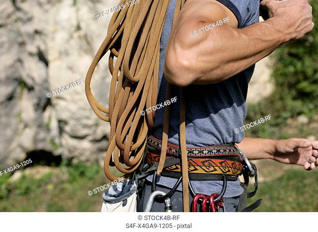 Young muscular man carrying a very long rope on his shoulder, selective focus