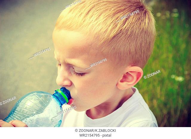 Little thirsty boy child drink water from bottle