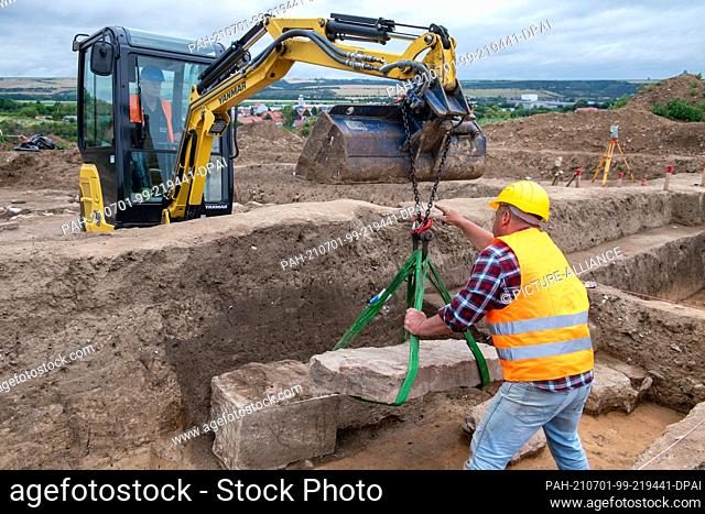 01 July 2021, Saxony-Anhalt, Eisleben: Excavation workers lift off the covering of a sarcophagus on the site of the former royal palace of Helfta