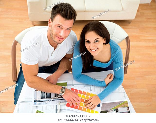 High Angle View Of Young Couple Choosing Color From Swatch
