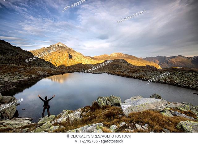 Hiker admires Lake Bergsee at sunrise Chiavenna Valley Spluga Valley Switzerland Europe