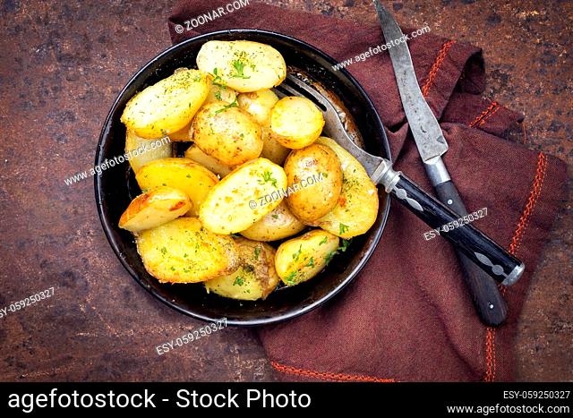 Roast Potatoes with herbs as top view in an iron cast pan