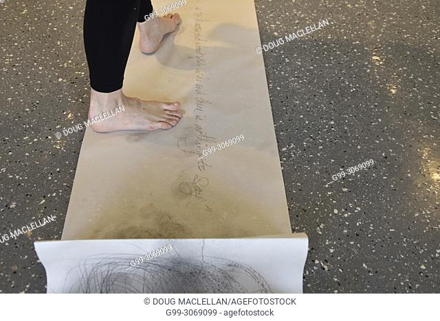 A rear view from the mid calf of a woman artist as she creates a performance art work at an artist run gallery in Windsor, Canada