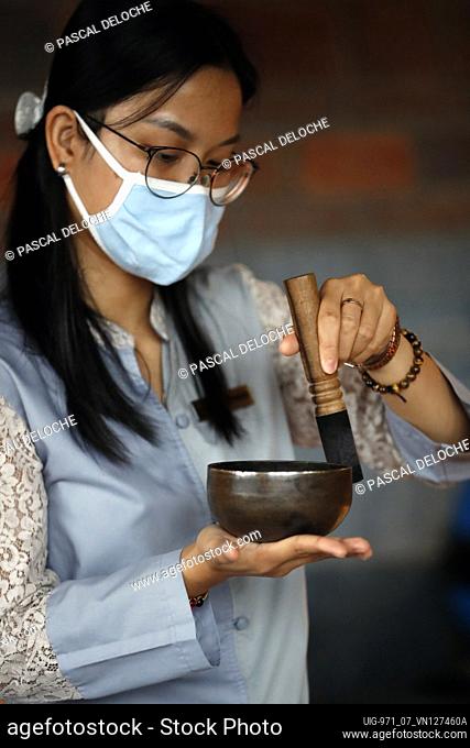Woman using a tibetan singing bowl. Self care, meditation, recreation, yoga and sound therapy. Vietnam