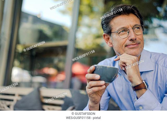 Mature businessman sitting in coffee shop, drinking coffee
