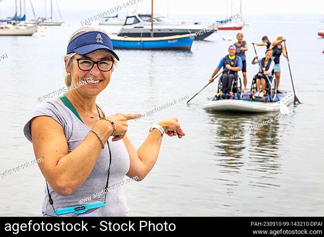 10 September 2023, Schleswig-Holstein, Eckernförde: Tanja Miranda, orransator of the wheelchair SUP event ""Rolli on SUP"" points to a paddle team at the Borby...