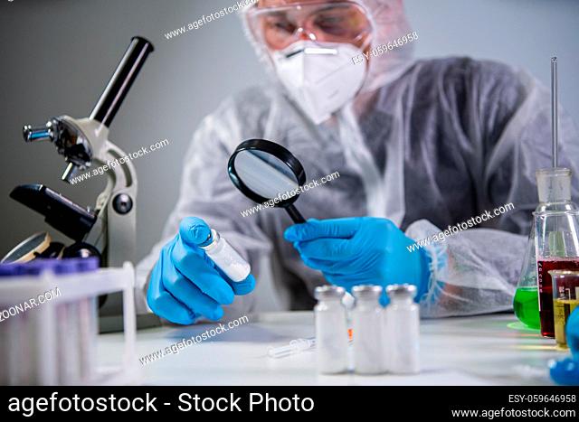 Healthcare and medical concept. Pharmaceutical research and clinical trials concept. Laborer in protective clothing dispenser and glasses is examining new...