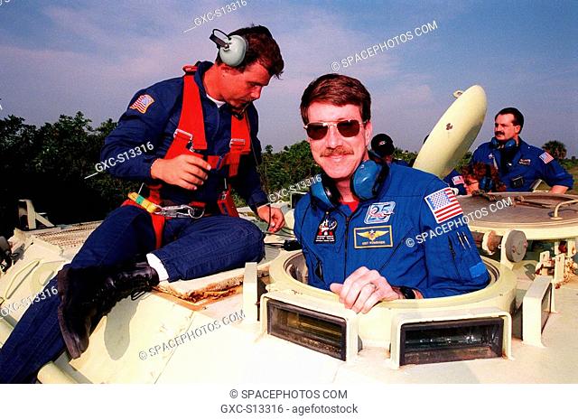 04/27/1999 --- Under the eye of Capt. Steve Kelly left, with Space Gateway Support, Commander Kent V. Rominger gets ready to practice driving the small armored...