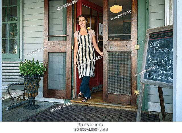 Female shop assistant in doorway of country store