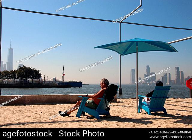 03 October 2023, USA, New York: People sitting on Manhattan's first beach, the Gansevoort Peninsula. At the end of summer, of all times