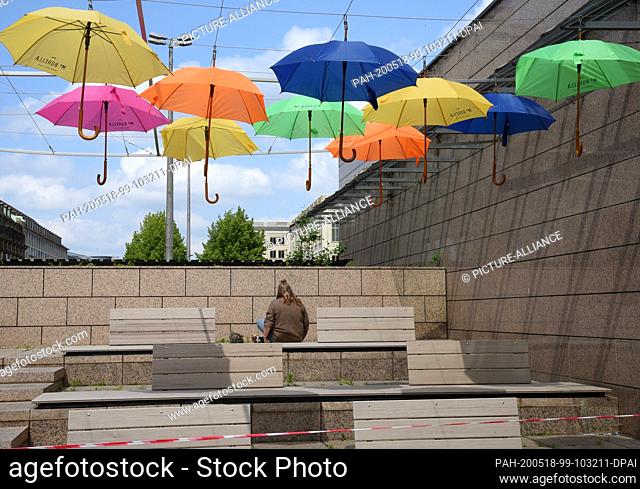 14 May 2020, Saxony, Leipzig: On Augustusplatz in Leipzig, a woman is sitting on a terrace area that is closed off because of corona