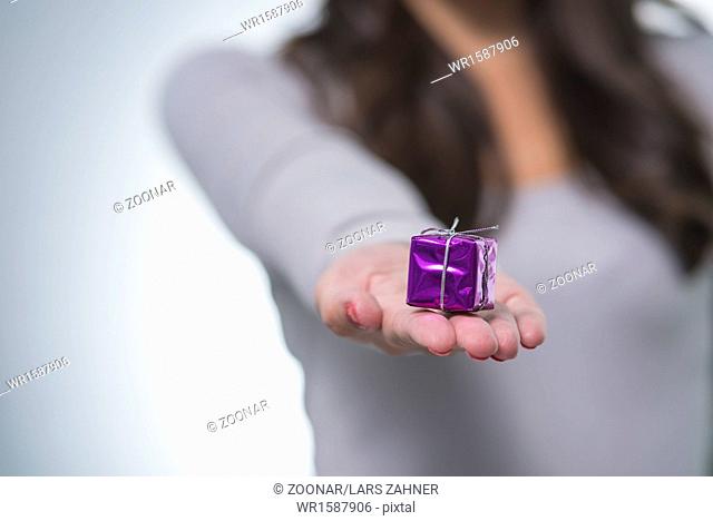 Pretty woman holding out a small purple gift