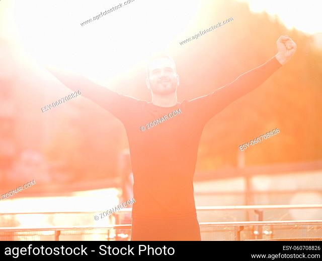 Full length portrait of sporty man raising arms towards beautiful glowing sunshine, Sport and life achievements, freedom and happiness emotional concept