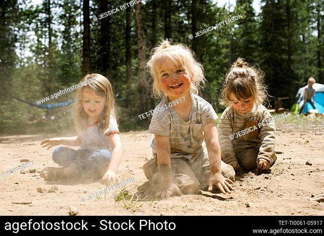 Three smiling girls (2-3, 4-5) playing in sand on camping, Wasatch-Cache National Forest