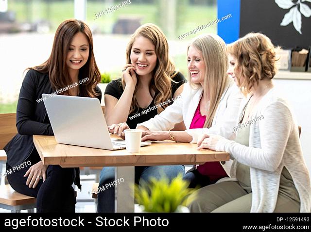 A group of business woman being trained by their team leader in a coffee shop at a place of business: Edmonton, Alberta, Canada