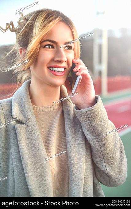 Cute smiling young woman talking on phone standing on the bride. Close up portrait
